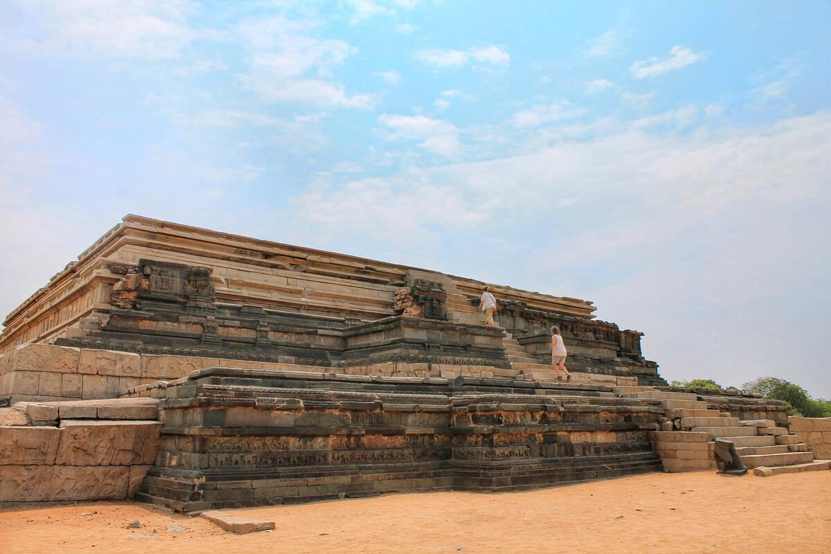 huge stepped stone platform covered in carvings with people for scale