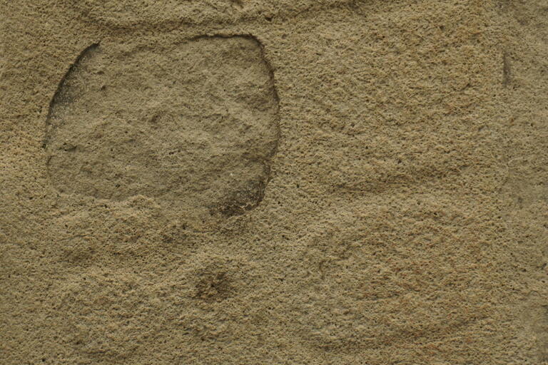 eroded stone bas-relief, vague rounded shapes visible at bottom
