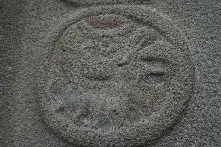 bas-relief stone carving, circle with vague bird shape inside