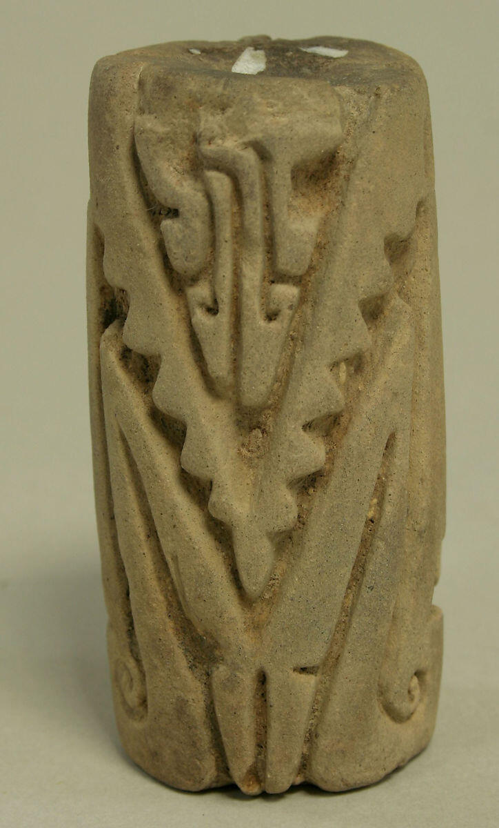 beige stone cylinder with triangular geometric carvings