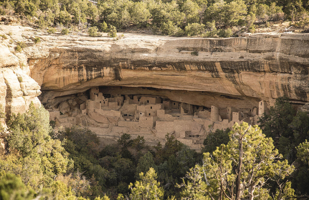 Mesa and cliff face. Multi-storey stone and masonry buildings are built into a deep overhang.