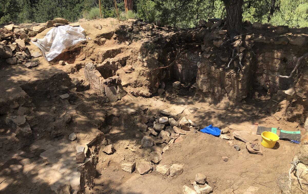 Archaeological site with excavated remains of walls and stone floor.