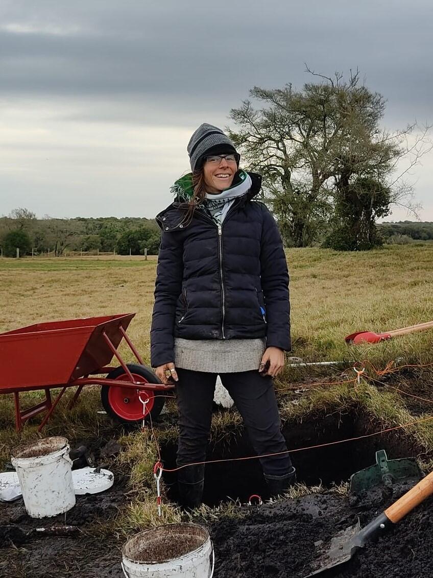 person standing in square hole with wheelbarrow in background