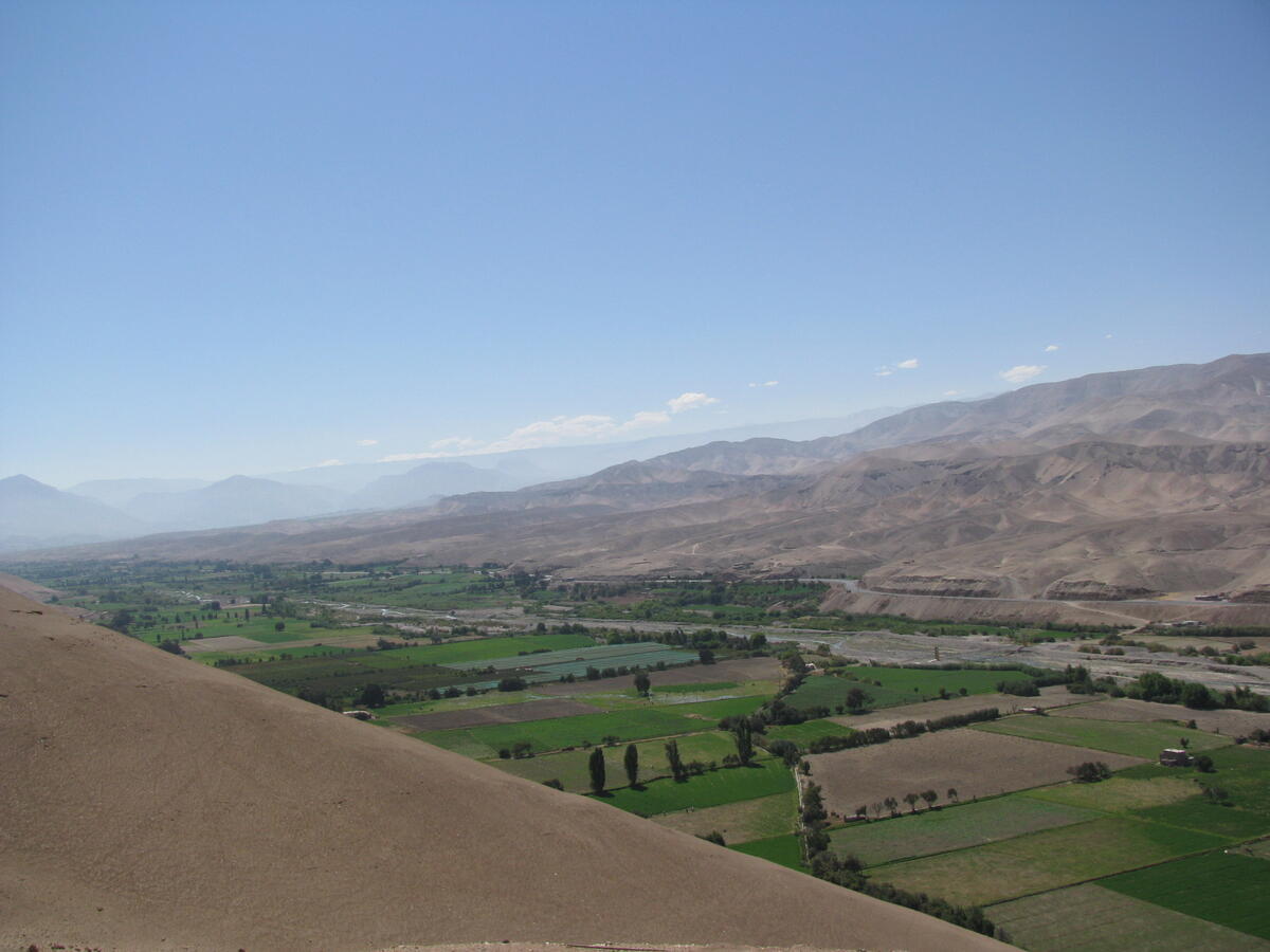 long valley with green fields, dry hills on either side