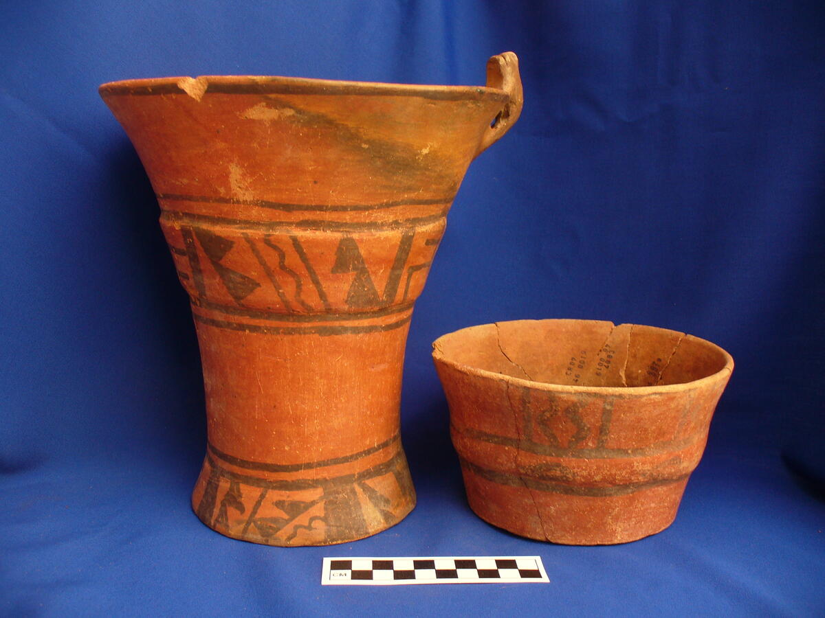 two ceramic vase-shaped vessels, red with dark brown geometric designs