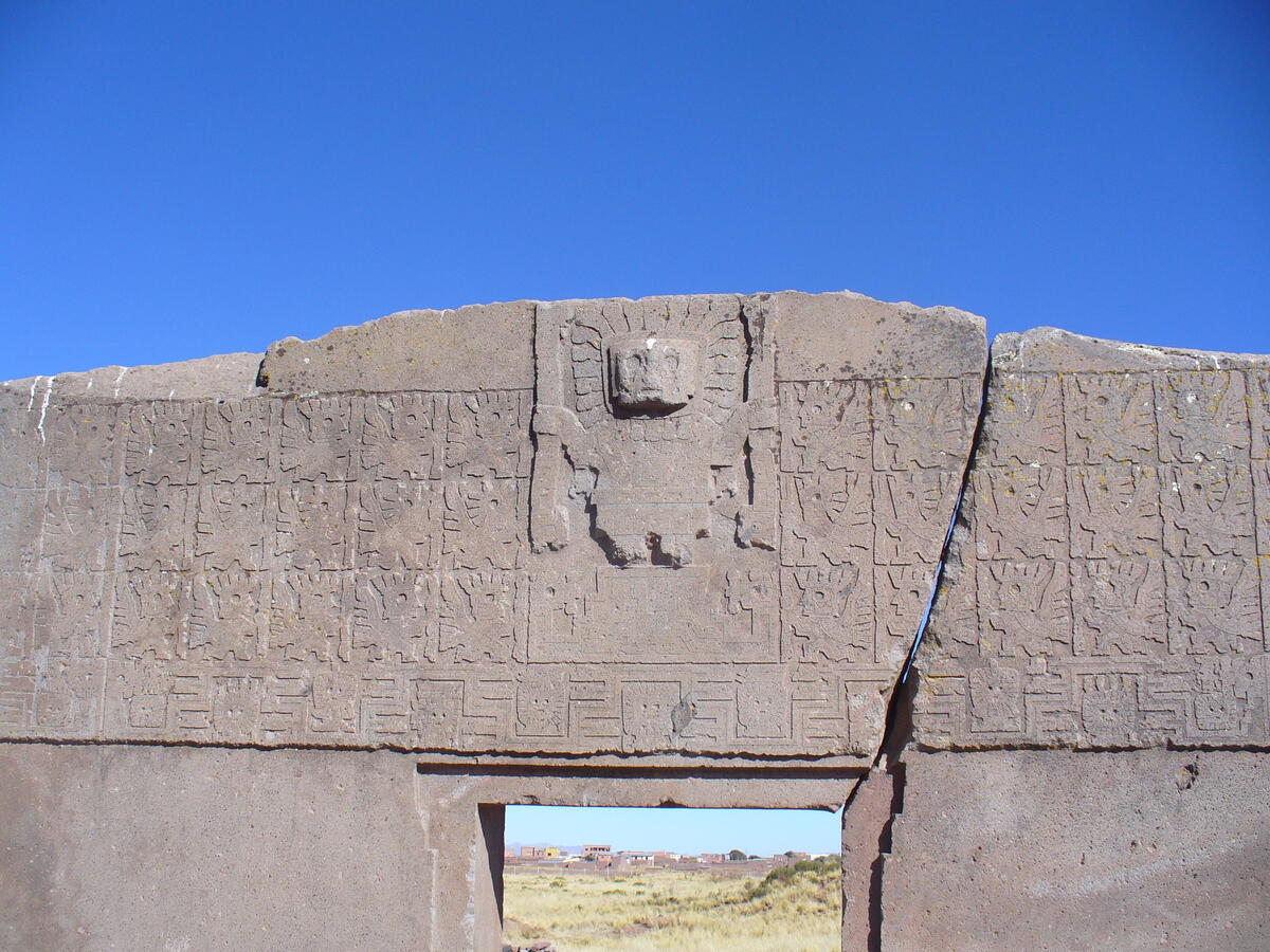 giant reddish carved stone gate with figure at center, top