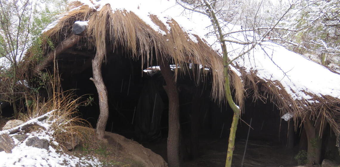 roof extending up from ground-level, snow on both roof and ground, interior visible between ground and roofline